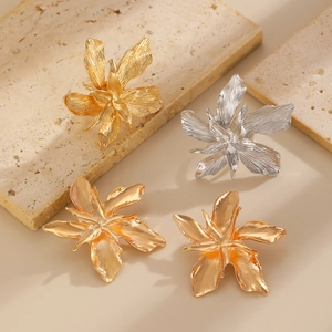 Detailed view of large metallic flower earrings in gold and silver with textured petals