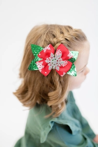 Detail of a Christmas glitter bow hair clip with snowflake on a young girl's hair