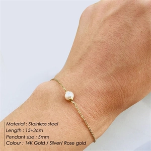 Close-up of double-layer stainless steel bracelet with a 5mm pearl on a woman's wrist