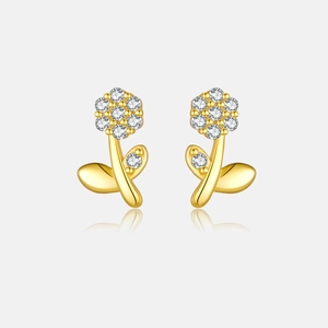 Macro shot of s925 gold flower earrings with sparkling zircons on a reflective base