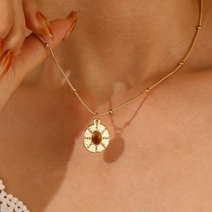Close-up of golden sun pendant with brown tiger eye stone on a beaded chain necklace