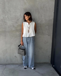 Detailed close-up of a white pleated sleeveless cotton shirt with a lace-up front design