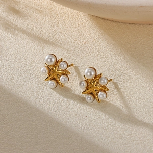 Detailed macro view of gold-plated starfish stud earrings featuring twelve white pearls