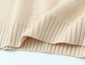 Close-up of thick beige ribbed knit texture and hem detail of the striped off-shoulder sweater
