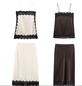 Detail of silk satin camisole set featuring delicate black lace trim on cream white fabric