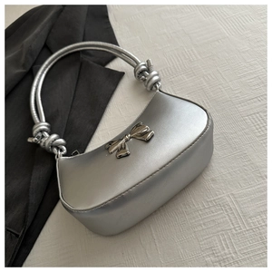 Detailed view of a silver crescent handbag featuring a metallic bow and knotted handle