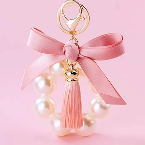 Portachiavi con fiocco di raso rosa perle bianche e nappa su anello metallico dorato