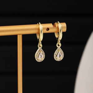 Detailed close-up of gold pear-cut drop earrings with sparkling micro-pave crystals