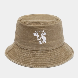 Close-up of khaki washed cotton bucket hat featuring white cow embroidery and metal eyelets