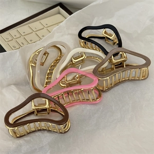 Close-up of elegant wavy resin hair claws with golden metal frames in assorted colors