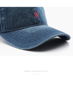 Close-up of red 'W' embroidery on vintage blue denim baseball cap with stitching detail