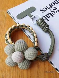 Macro detail of hand-woven green phone wrist strap with 3D knitted flower and pad