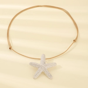 Detail of silver starfish pendant with shimmering crystals on a beige woven cord necklace