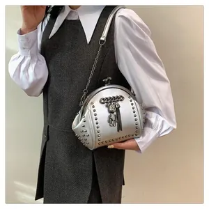 Detailed view of silver shell-shaped bag with metal rivets and bear pendant with tassels