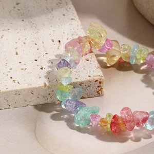 Macro detail of colorful natural stone elastic bracelet on a white travertine stone background