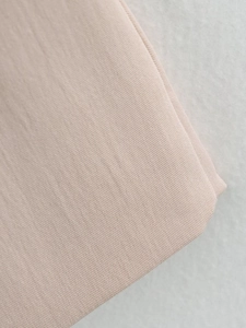 Close-up of the light pink twill fabric texture and fine stitching of the sleeveless dress