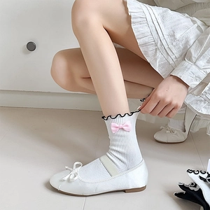Close-up of white JK socks with black wavy lace trim and cute pink bow detail