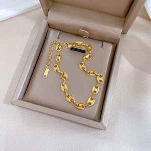 Detail of gold coffee bean chain bracelet with S.STEEL engraving on a jewelry box