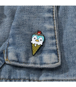 Detailed view of a cute penguin ice cream enamel pin on a blue denim jacket collar