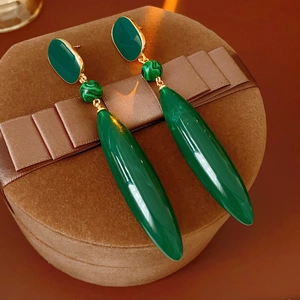 Detail of vintage gold earrings with green malachite beads on a brown velvet jewelry box
