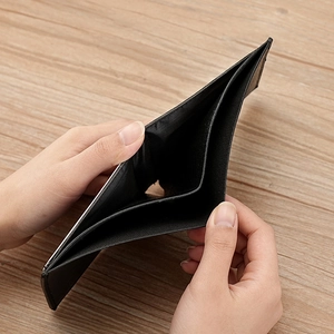 Mens short bi-fold soft PU leather wallet in black shown open on a wooden background
