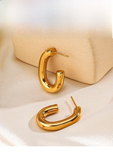 Detailed view of chunky C-shape 18K gold-plated stainless steel earrings on beige stone