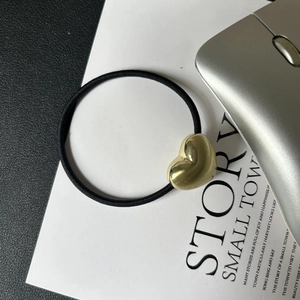 Detailed close-up of a high-elastic black hair tie with a polished gold heart-shaped charm