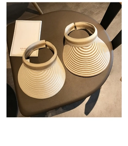Detail of wide brim straw sun hats with woven texture and open top on a leather seat