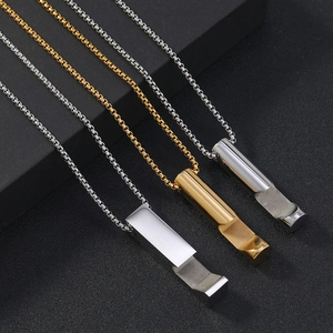 Macro shot of silver and gold whistle pendants on geometric stainless steel necklaces