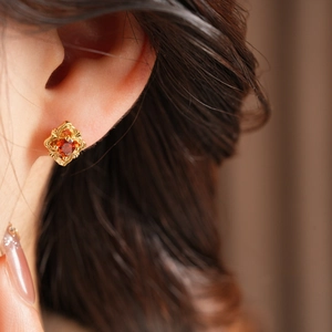 Macro view of vintage gold stud earrings with a red gemstone and ornate filigree