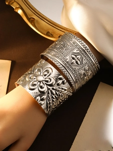 Nahaufnahme der goldenen Vintage-Armreifen mit floralen und geometrischen Mustern