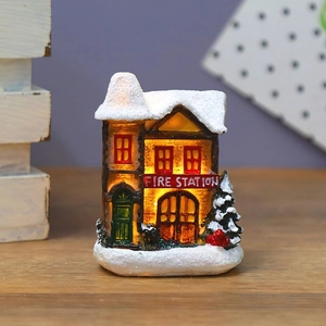 Detail of miniature Christmas fire station with warm LED light and artificial snow