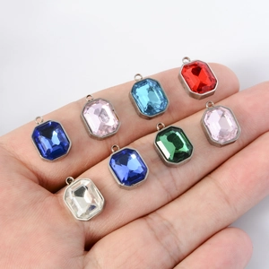 Colorful faceted rectangle crystal pendants in silver frames shown on a palm