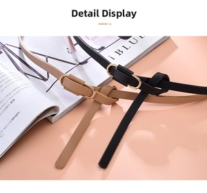 Detail of minimalist thin waist belts in black and camel leather with gold oval buckles