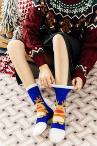 Close-up of fluffy blue Christmas socks with yellow reindeer embroidery and white trim