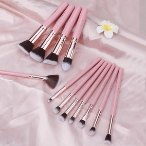Close-up of 13-piece pink makeup brush set with rose gold ferrules on satin silk