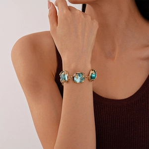 Detail of vintage gold bracelet with teal resin stones and delicate gold leaf charms