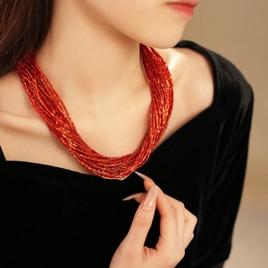 Dettaglio della collana a più fili di perle rosse con design retrò su velluto nero