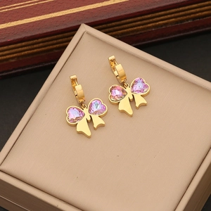 Golden bow earrings with purple heart gemstone on a beige jewelry gift box