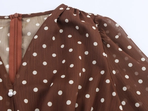 Détail d'une robe en mousseline marron à pois avec fermeture zippée et bouton perle élégant