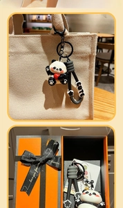 Detail of cute panda keychain with red heart on canvas bag with orange gift box