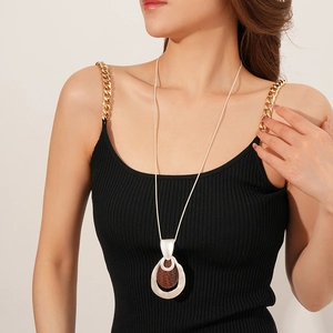 Detail of silver water-drop pendant with brown woven texture on a long necklace
