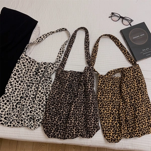 Tre borse tote leopardate in beige, caffè e giallo senape su un lenzuolo bianco