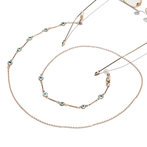 Fashionable gold evil eye glasses chain with blue beads and metal links on white