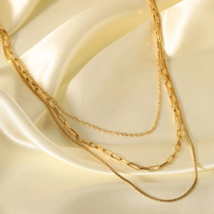 Three-layer 18K gold plated stainless steel necklace on a soft yellow satin background