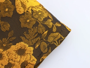 Macro view of dark brocade fabric with golden floral embroidery for vintage dress