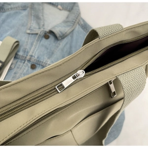 Detail of beige canvas tote bag with metal zipper and front pocket for daily use