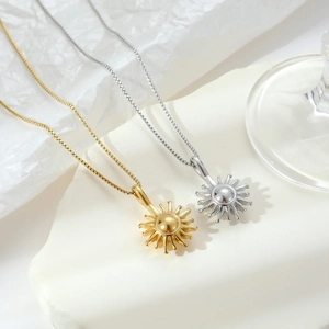 Polished sunburst pendant necklace in gold and silver finish on minimalist stand