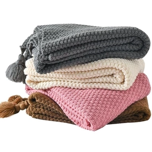 Stacked waffle knit blankets in grey, white, pink and brown with tassel details