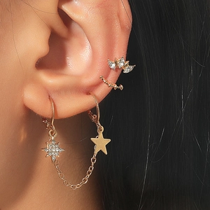 Detail of vintage geometric gold ear cuffs set with zircon stars worn on ear model
